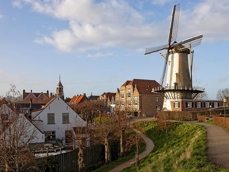 A view of a windmill down a street in Willemstad, Netherlands A view of a windmill down a street in Willemstad, Netherlands